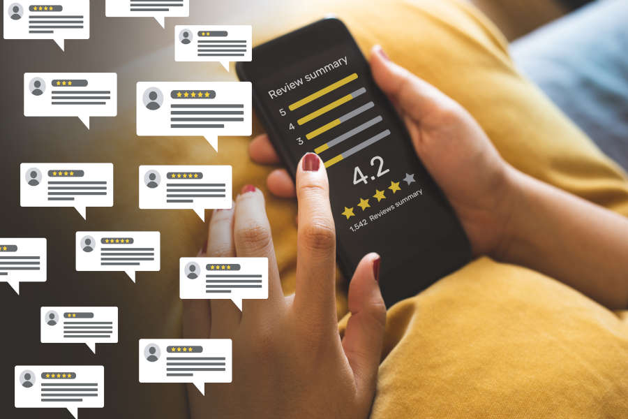 Person sitting on a couch with a yellow pillow and black phone looking at small business reviews