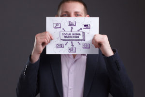 A man in a dress shirt and jacket holding up a piece of paper with social media marketing print and designs in Central IL.